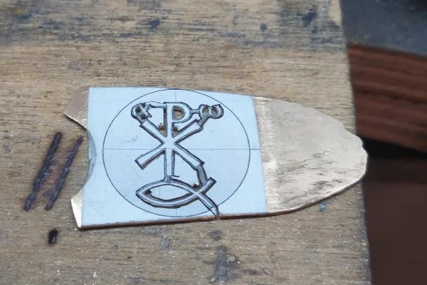 cut out Christian symbols from gold plate for making religious medals