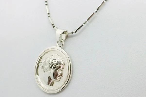 silver medal with engraving of a Greek face from a photo